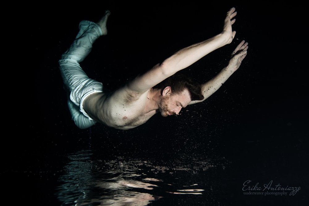 Onderwaterfoto model man in witte broek, met weerspiegeling