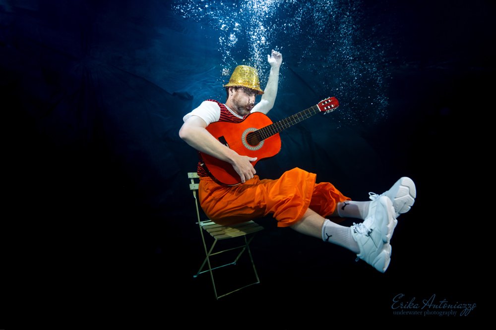 Onderwaterfoto model man in oranje kleding met gitaar