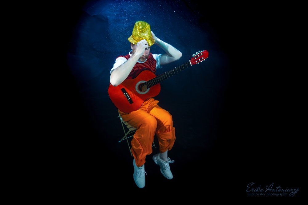 Onderwaterfoto model man in oranje kleding met gitaar