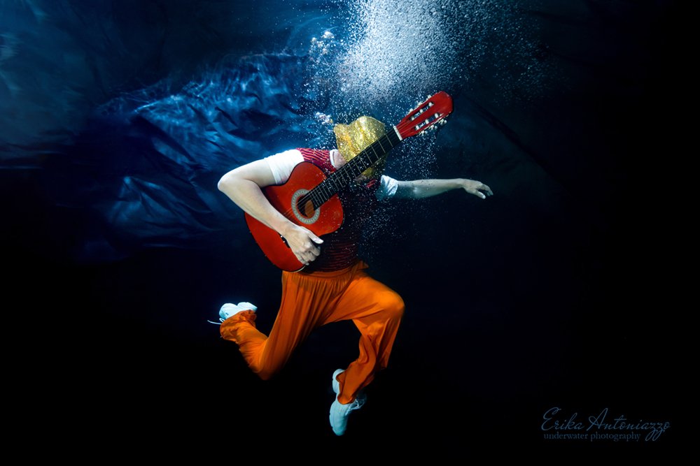 Onderwaterfoto model man in oranje kleding met gitaar