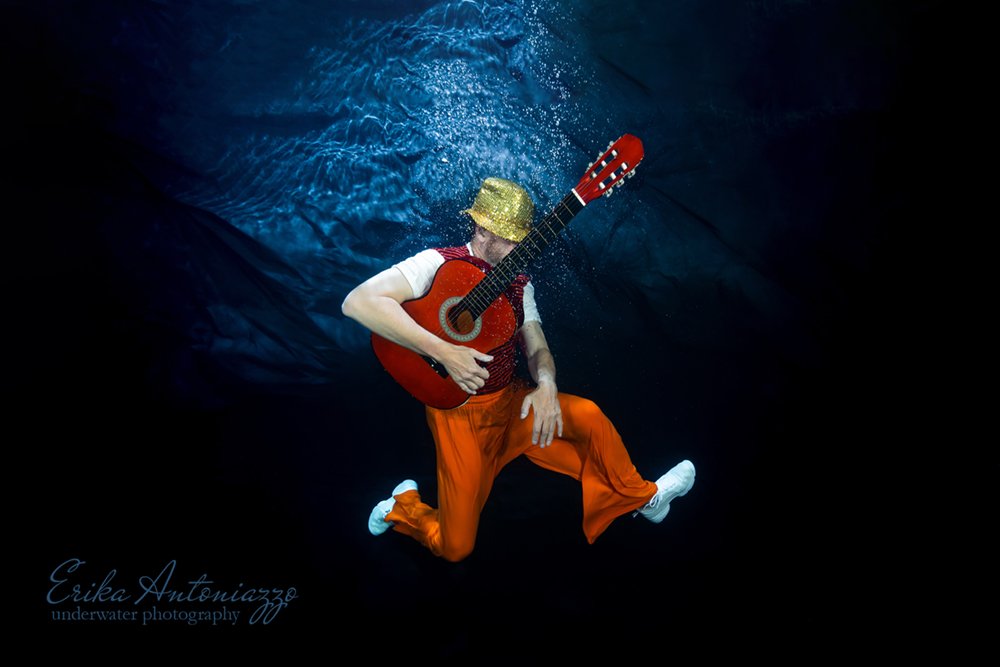 Onderwaterfoto model man in oranje kleding met gitaar