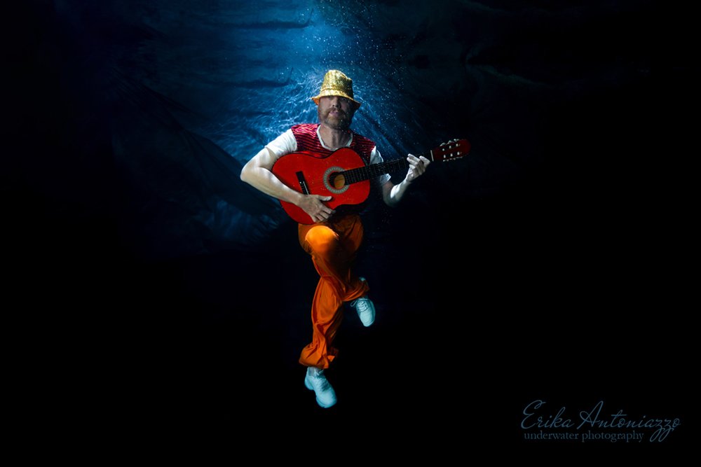 Onderwaterfoto model man in oranje kleding met gitaar