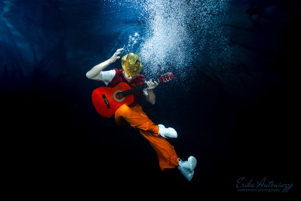 Onderwaterfoto model man in oranje kleding met gitaar