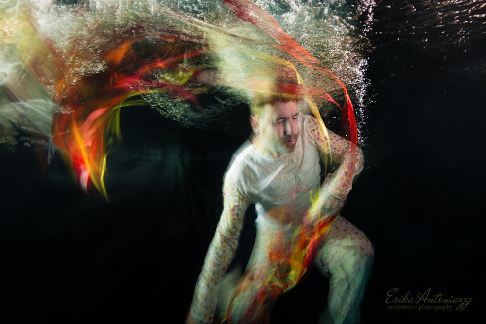Onderwaterfoto model man in wit en oranje kleding, bewogen beeld, artistiek