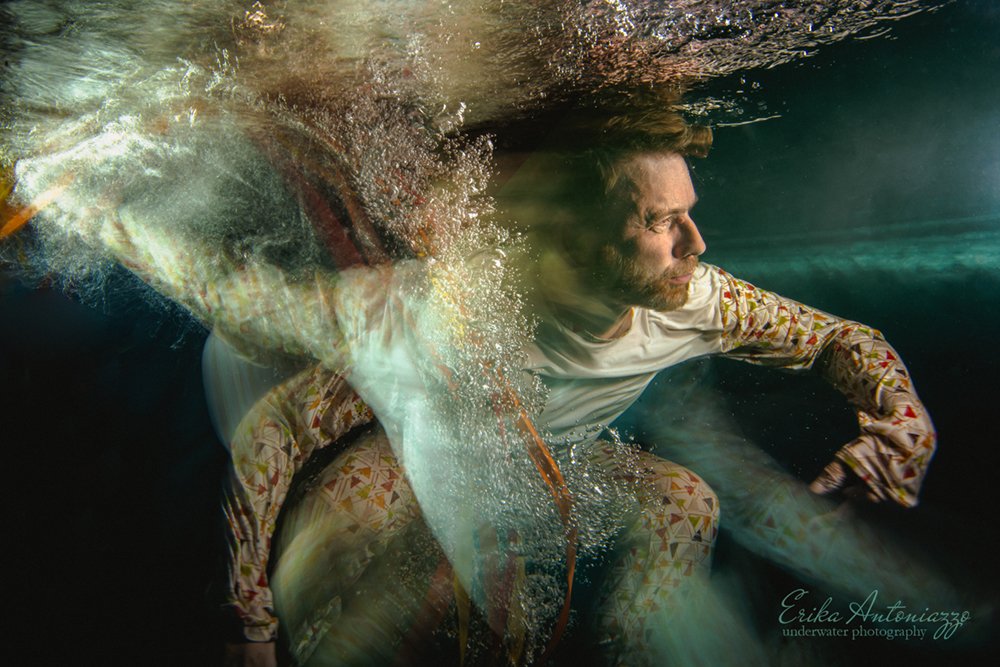 Onderwaterfoto model man in wit en oranje kleding, bewogen beeld, artistiek