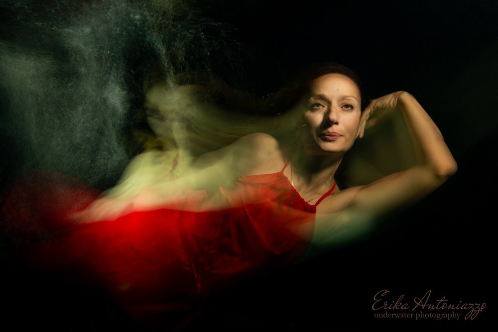Onderwaterfoto model vrouw in rode jurk, bewogen beeld, artistiek