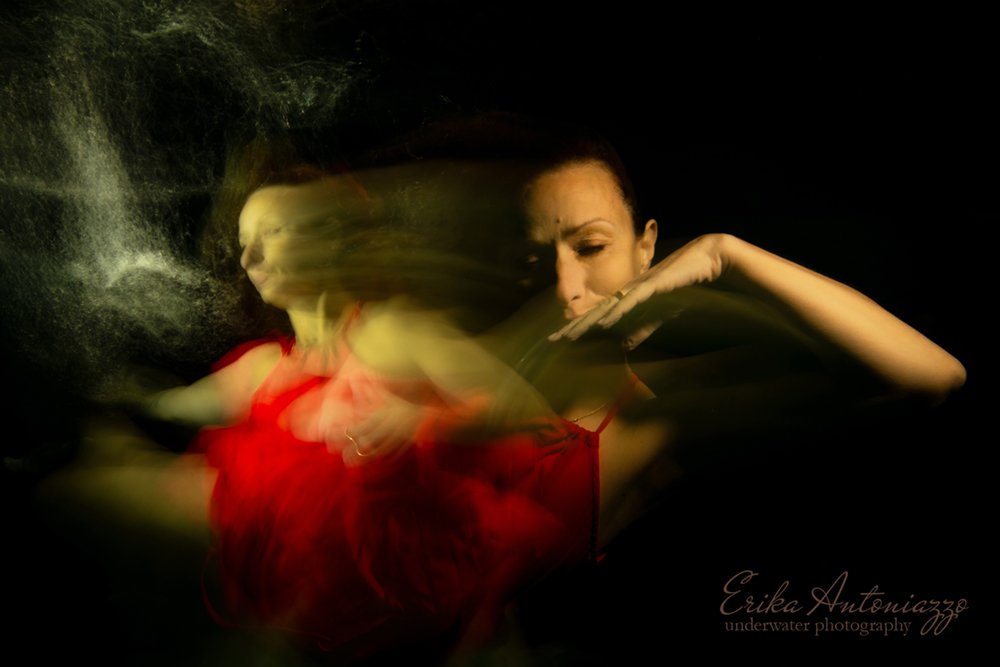 Onderwaterfoto model vrouw in rode jurk, bewogen beeld, artistiek