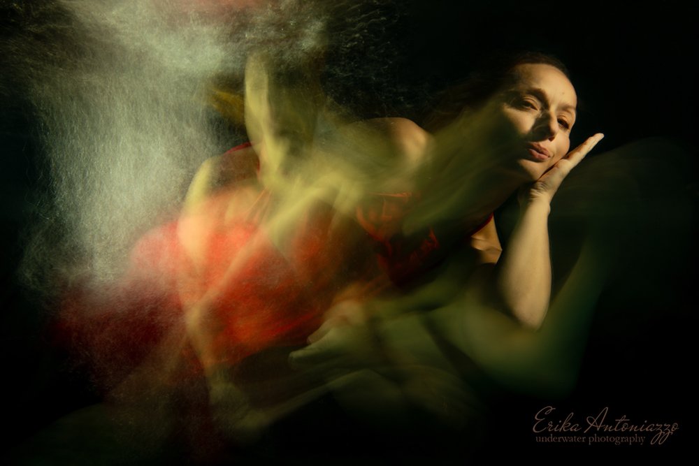 Onderwaterfoto model vrouw in rode jurk, bewogen beeld, artistiek