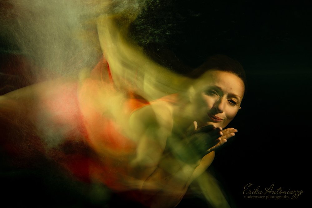 Onderwaterfoto model vrouw in rode jurk, bewogen beeld, artistiek