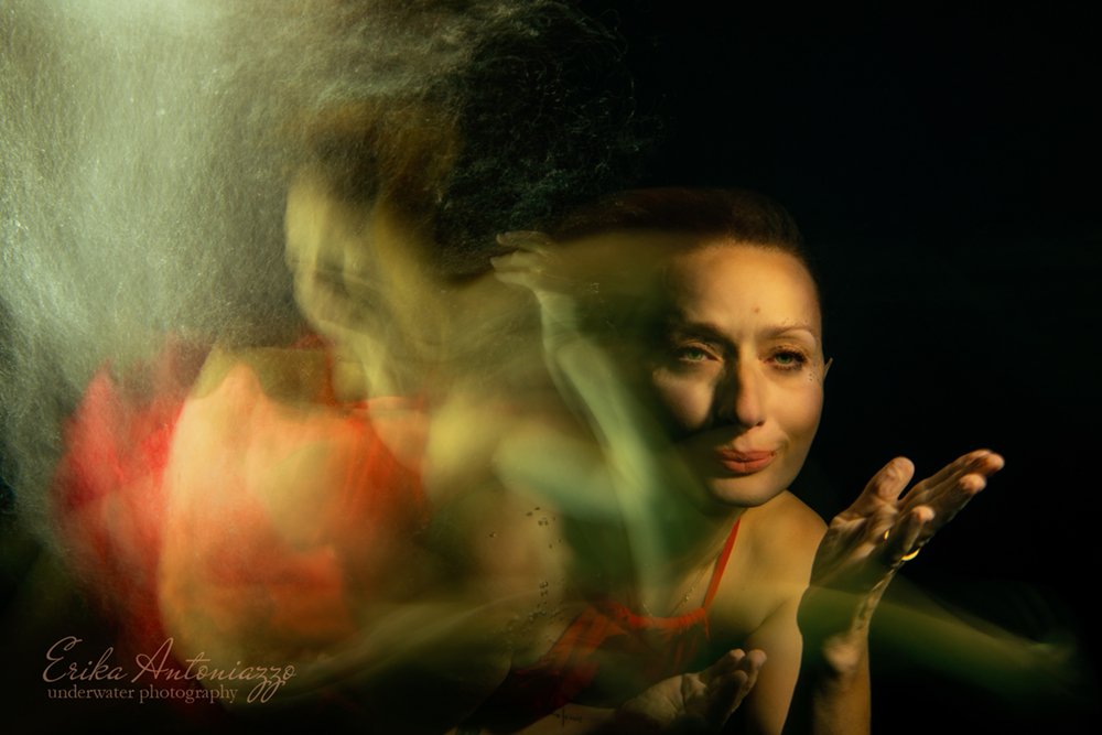 Onderwaterfoto model, vrouw in rode jurk, artistiek bewogen beeld