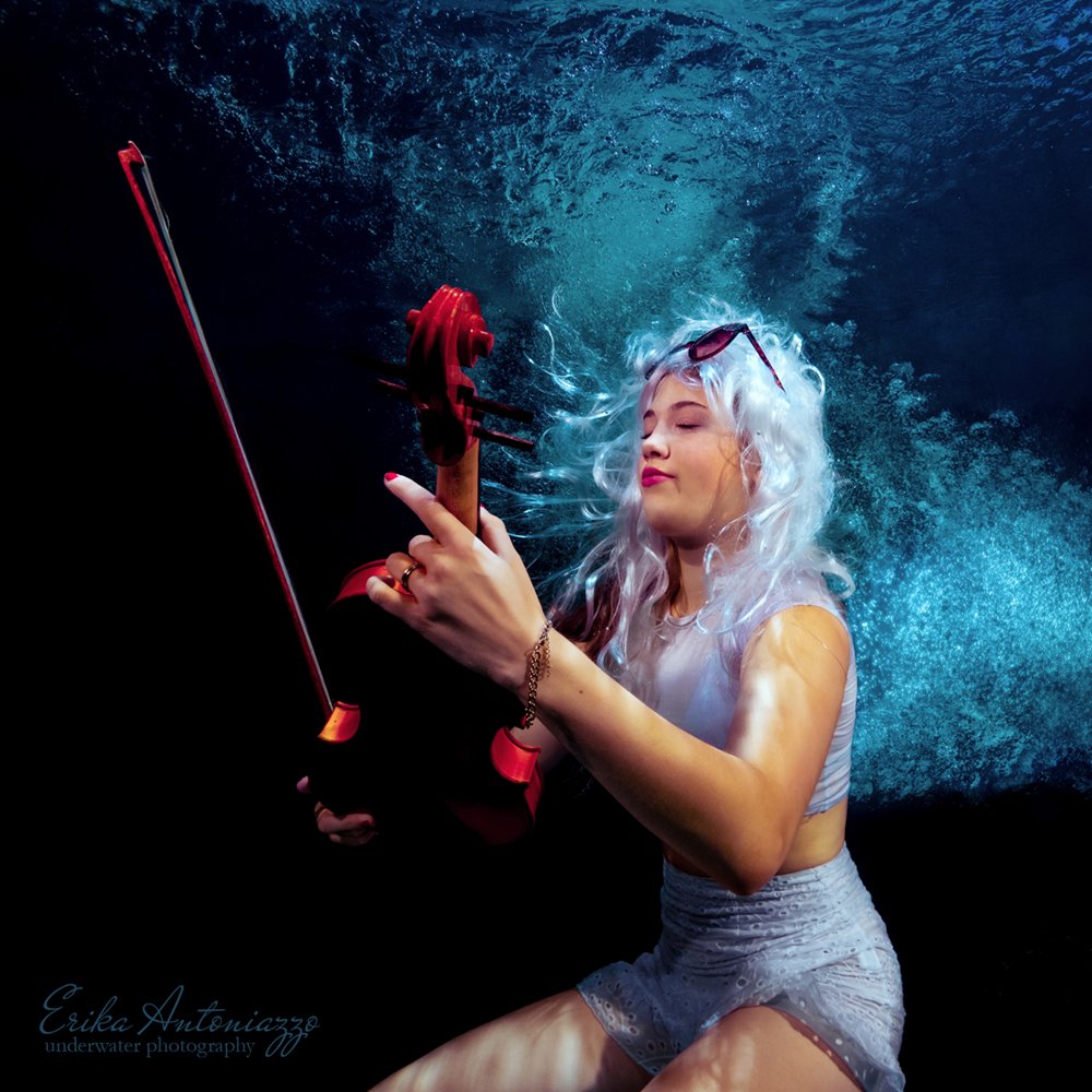 Onderwaterfoto model jonge vrouw met wit haar in wit topje en rokje, met viool