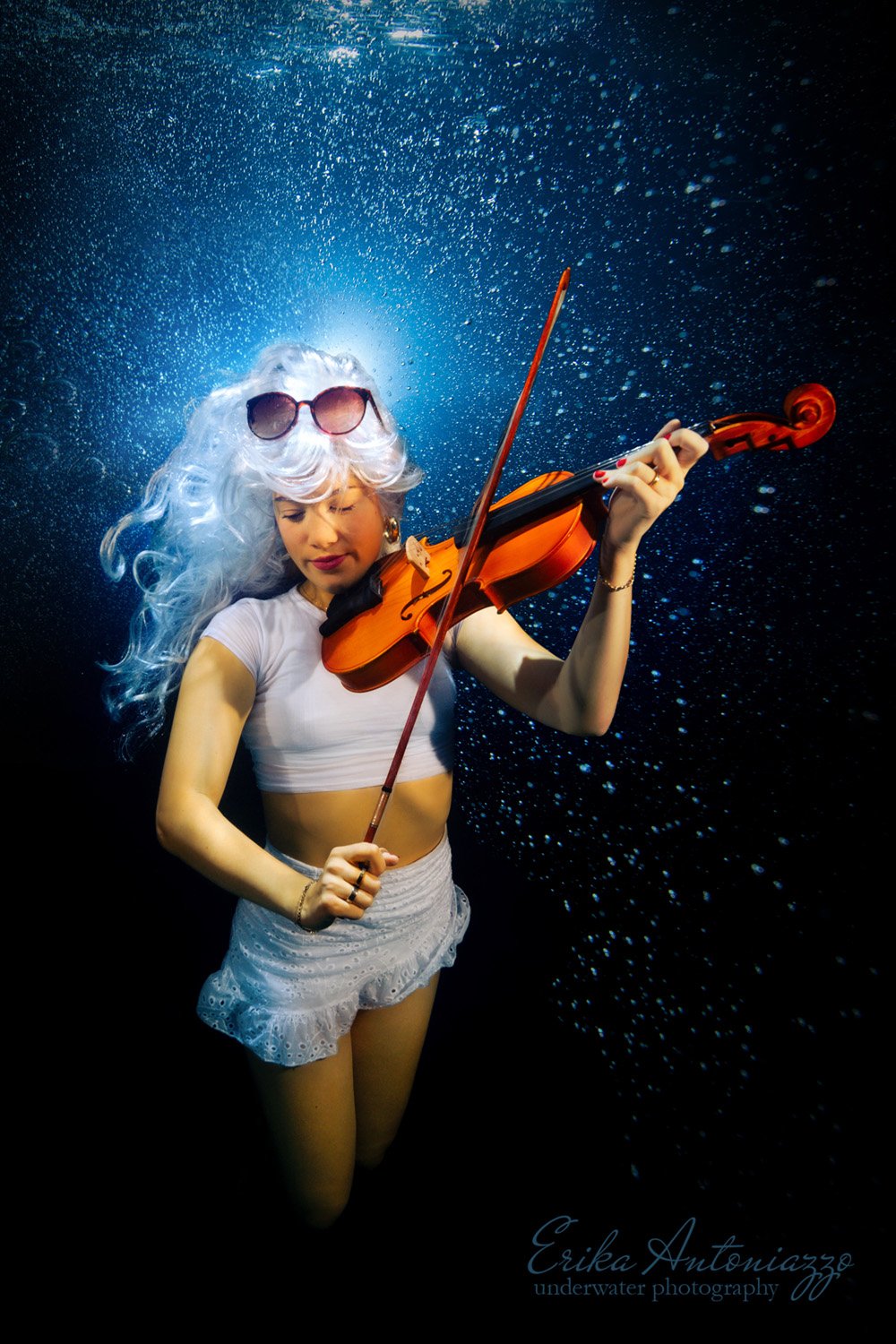 Onderwaterfoto model jonge vrouw met wit haar in wit topje en rokje, met viool
