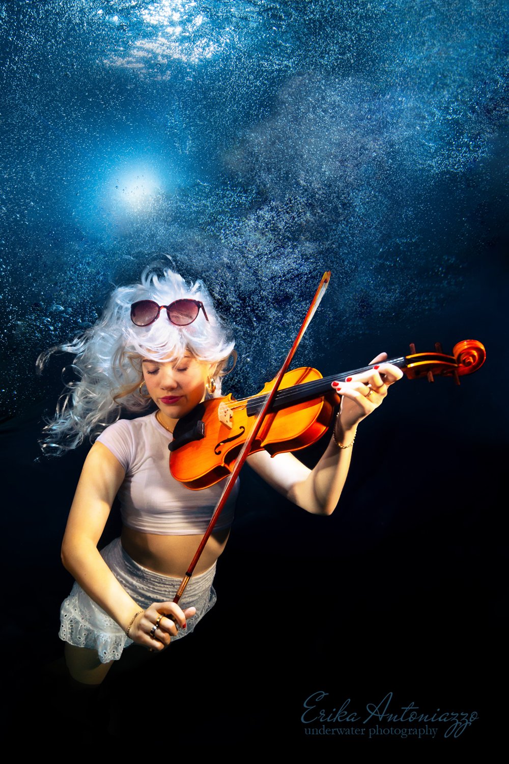 Onderwaterfoto model jonge vrouw met wit haar in wit topje en rokje, met viool