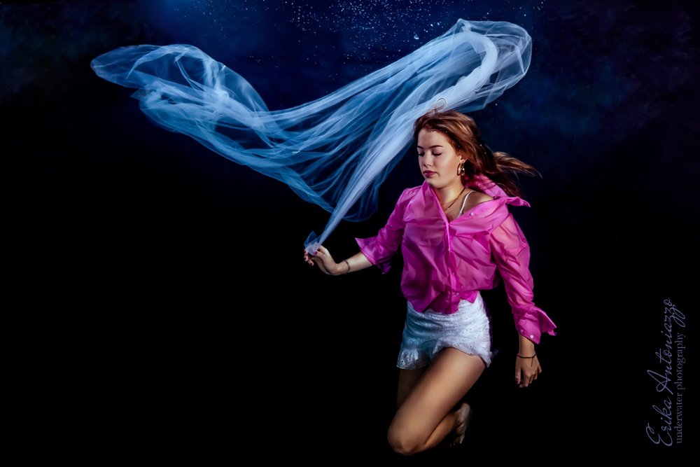 Onderwaterfoto model, jonge vrouw in fuchsia bloes en wit rokje met witte sluier