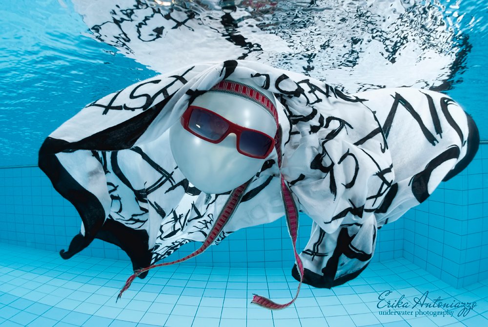 Witte ballon met zonnebril, bandanna en zwart-witte doek onder water in het zwembad