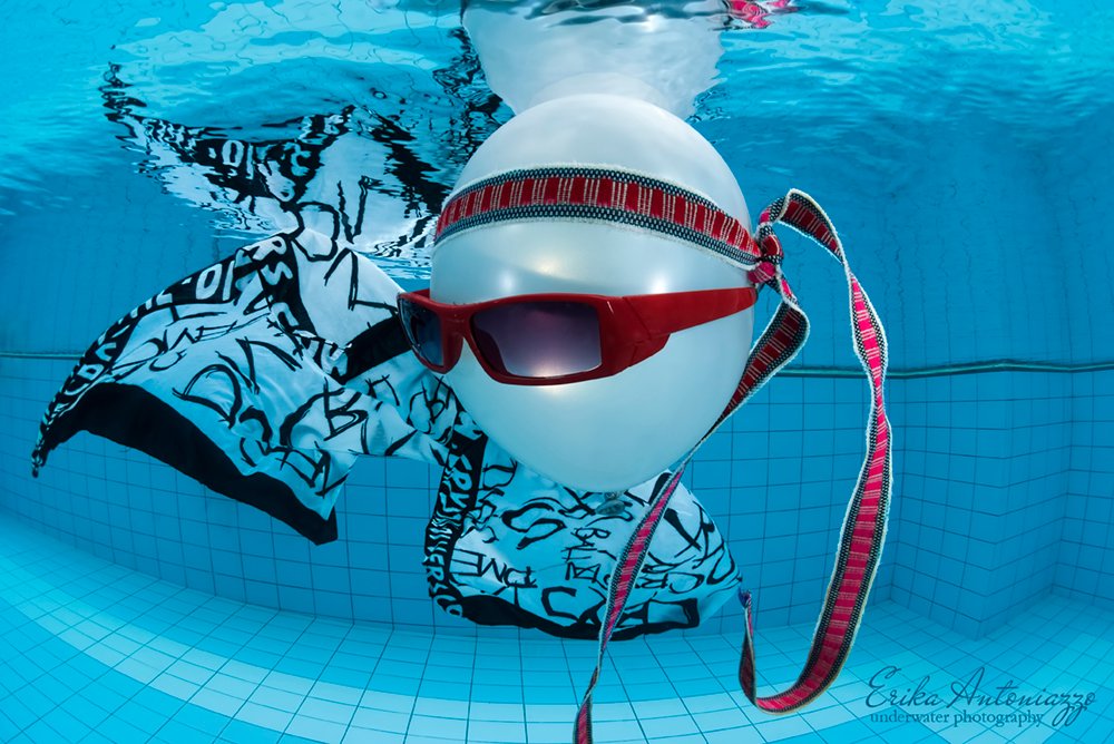 Witte ballon met zonnebril, bandanna en zwart-witte doek onder water in het zwembad