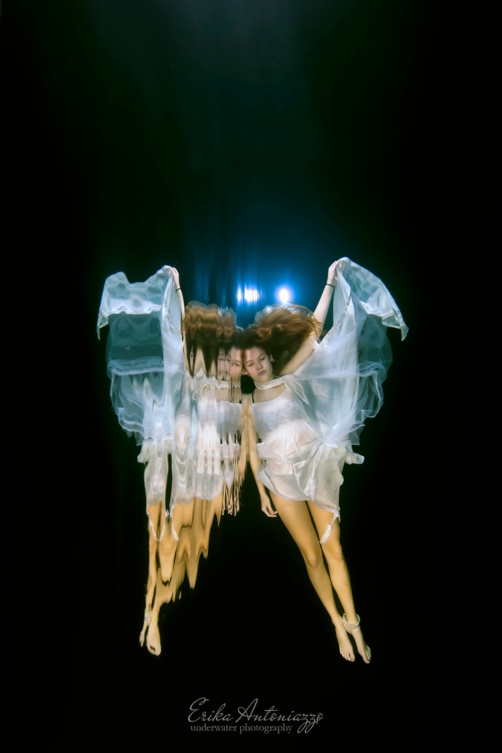 Onderwaterfoto model, jonge vrouw met witte sluiers aan armen en benen