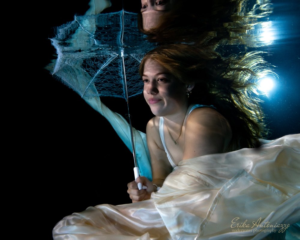 Onderwaterfoto model, jonge vrouw met witte sluier en parasol
